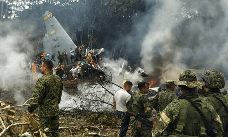 Soldados e equipes de resgate perto de um Hércules da Força Aérea emitindo fumaça densa após a aeronave ter caído durante a decolagem em Puerto Leguizamo, Colômbia. (Daniel Ortiz/AFP)