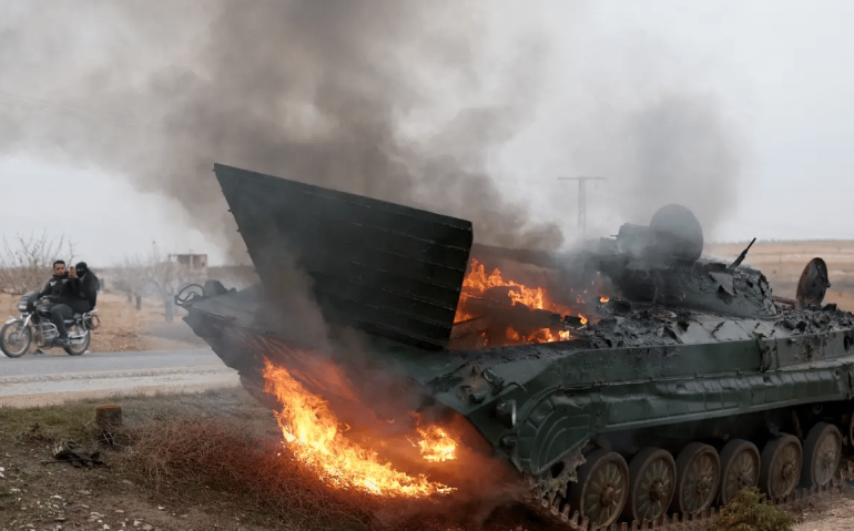 Tanque do exército sírio é queimado pela ação de radicais do HTS, grupo jihadista que busca a derrubada do governo (OMAR HAJ KADOUR/AFP)