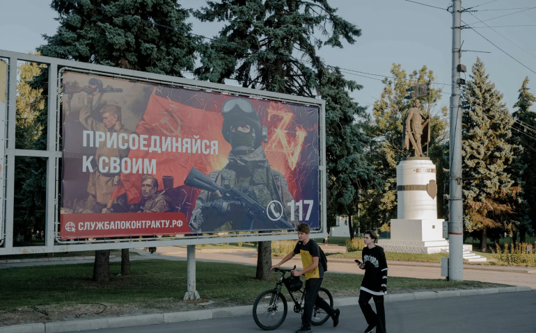 Um sinal de recrutamento militar em Kursk, na Rússia, em agosto. O presidente Vladimir Putin ordenou a adição de 180 mil novos membros às fileiras militares russas, elevando o número para 1,5 milhões.Crédito...Nanna Heitmann para o The New York Times