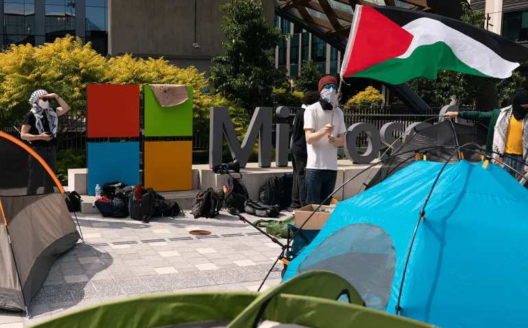 Manifestante segura uma bandeira palestina perto de tendas durante um protesto na sede da Microsoft em Redmond, Washington, EUA. 19/08/2025 - (David Ryder/Getty Images)