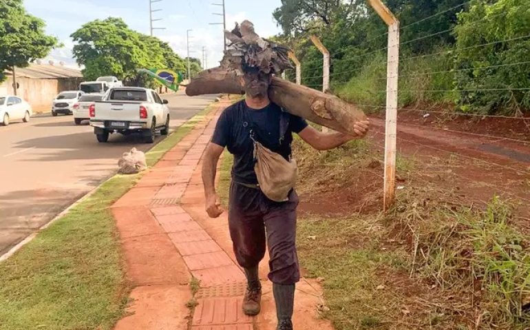 Joaquim caminha com tronco de madeira que pesa, segundo ele, mais de 30 aquilos. (Foto: Ângela Kempfer) - CREDITO: CAMPO GRANDE NEWS