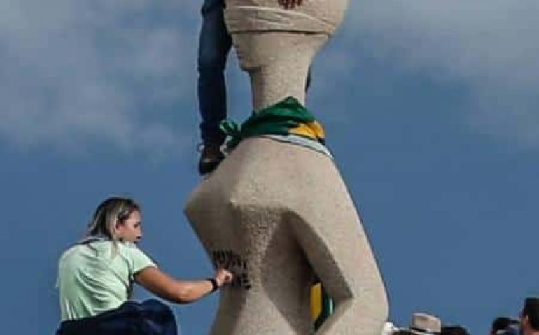 8.jan.2023 - Mulher põe uma das mãos na pichação 'Perdeu, mané' feita na estátua 'A Justiça', durante invasão às sedes dos Três Poderes Imagem: Gabriela Biló-8.jan.23/Folhapress