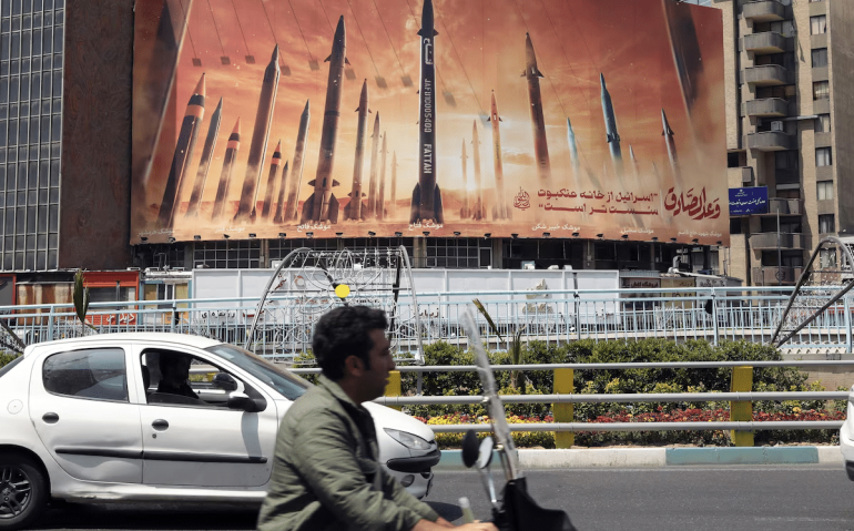 Iranianos passam por um outdoor anti-Israel com fotos de mísseis iranianos em Teerã, no Irã: o país lançou drones e foguetes em direção a Israel em 13 de abril  Foto: Abedin Taherkenareh/EFE