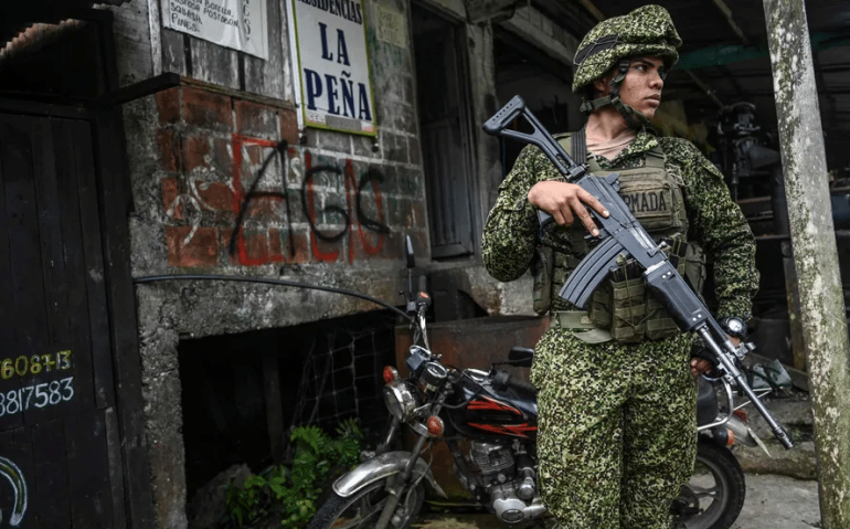 Soldado colombiano monta guarda ao lado de pichações de guerrilheiros no departamento de Vale do Cauca — Foto: Joaquin Sarmiento/AFP