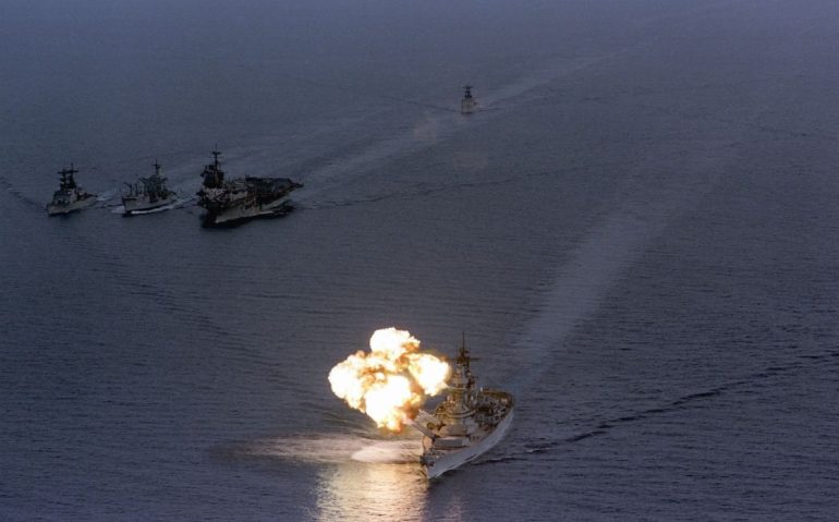 USS Iowa dispara ao entardecer, com o USS Saratoga ao fundo