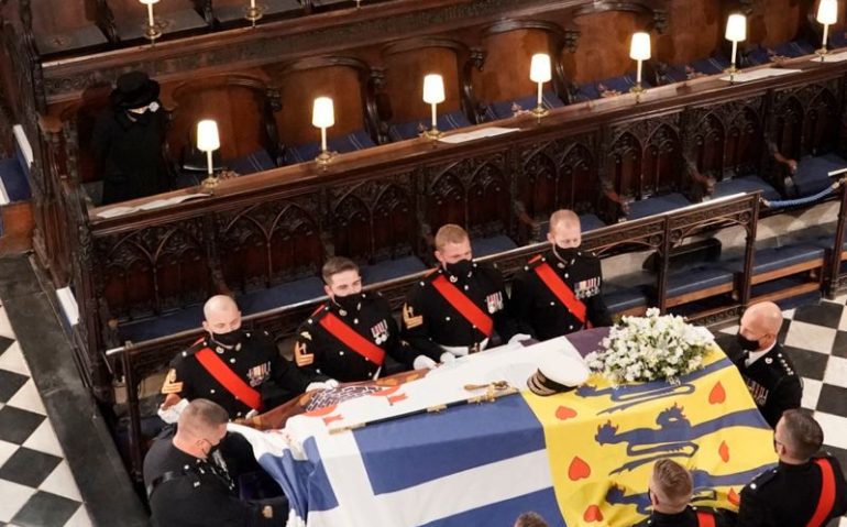 Guarda fúnebre do Príncipe Philip cobre o ataúde com sua bandeira pessoal, que representa o Brasão de Armas Dinamarquês, a bandeira da Grécia, a família Mountbatten e também o castelo de Edimburgo. (Imagem: BBC)